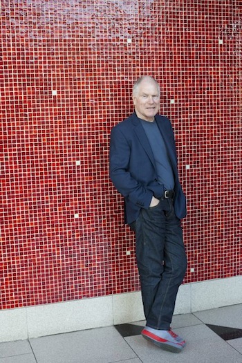 Portrait of Derek Power leaning against red mosaic wall